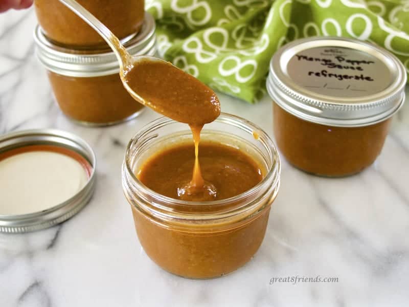 Lifting a spoonful of Mango Pepper Sauce from jar.