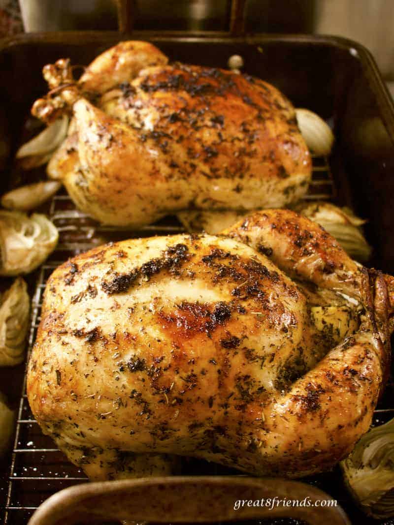 Two whole roast chickens in roasting pan.