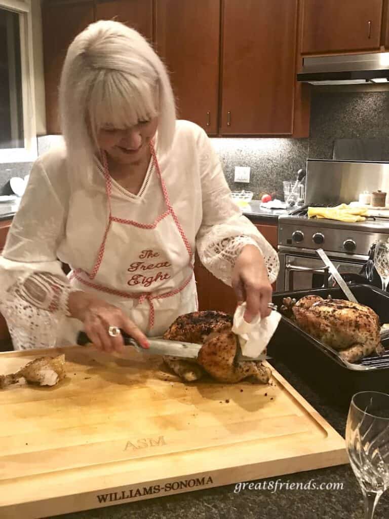 Carving roasted chicken and the second one in the roasting pan.
