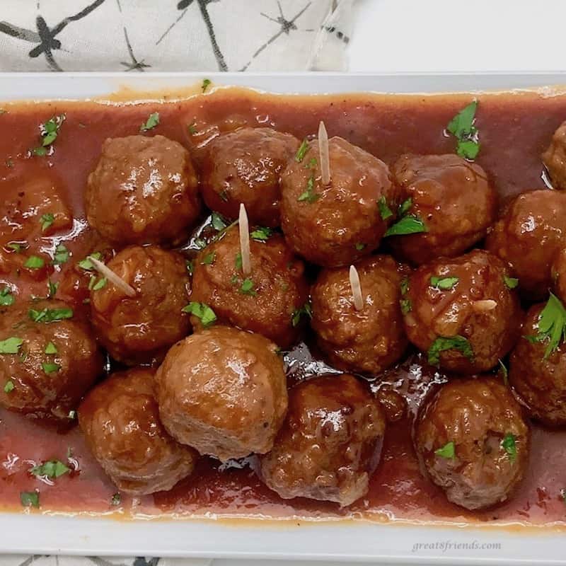 Up close photo of Hawaiian Meatballs on a platter with sauce and toothpicks for eating.