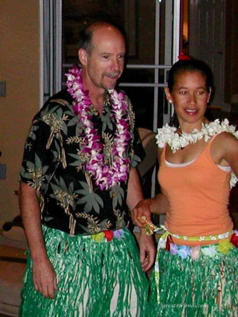 A man and woman with leis on a green grass skirts on.