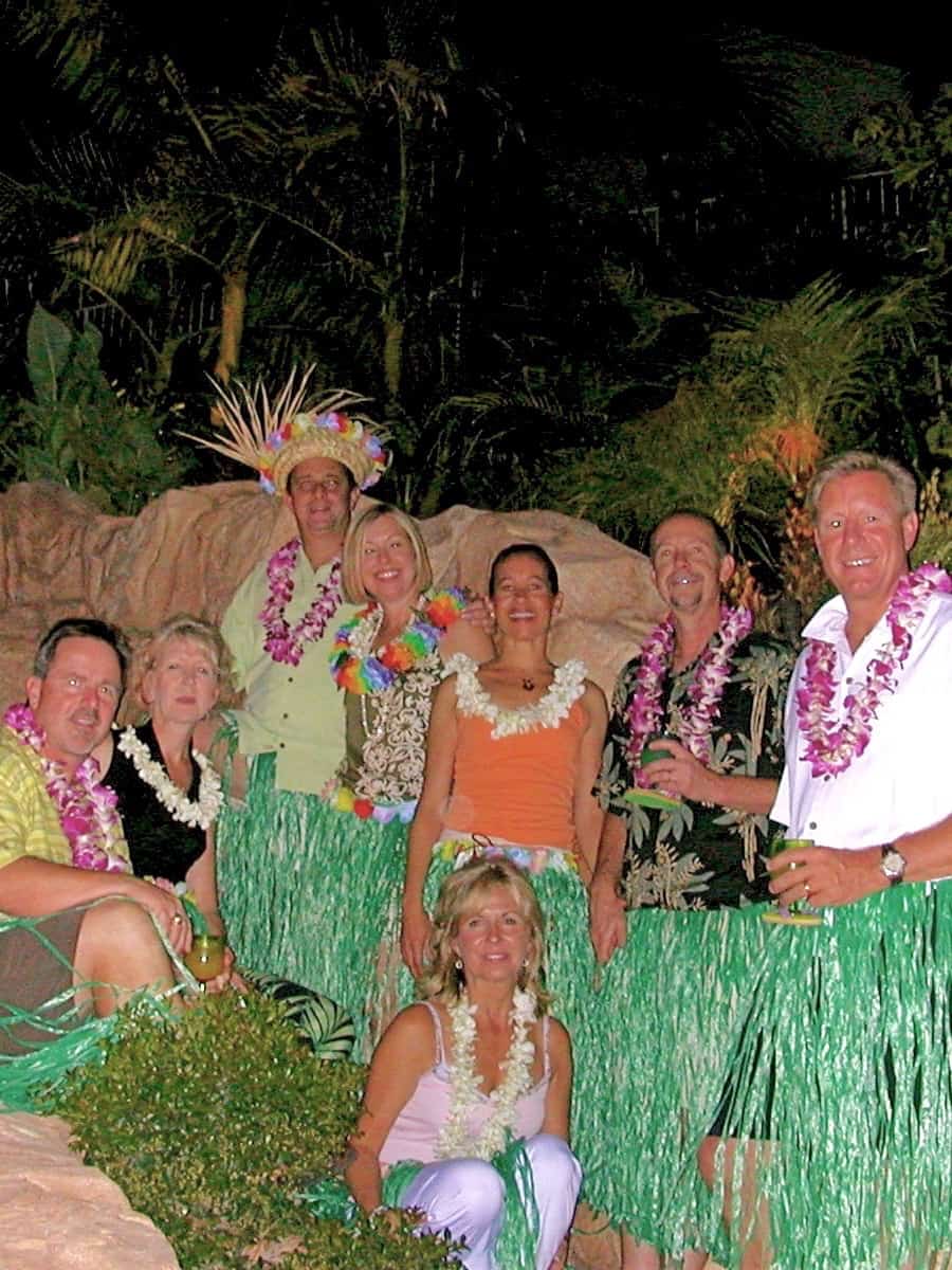 Eight people posing with grass skirts and leis on.
