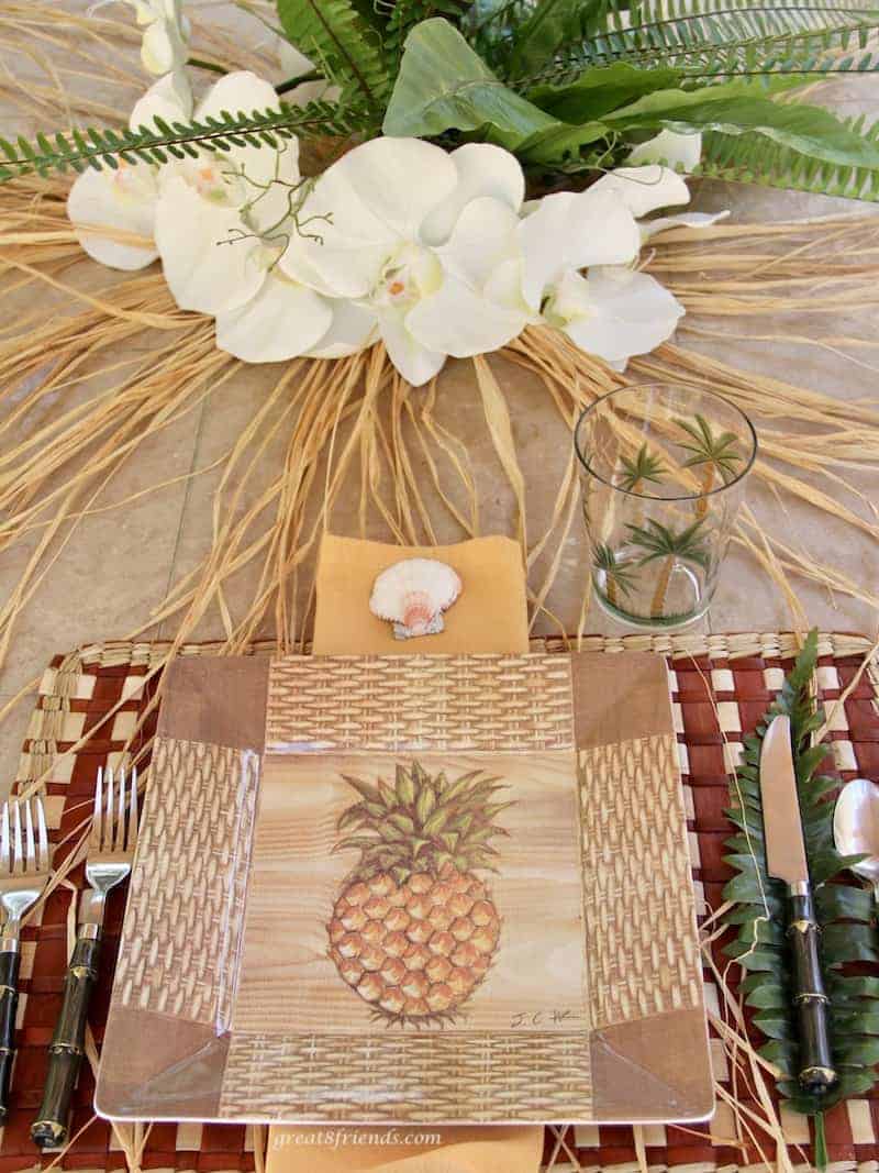 Place setting using for a Luau dinner party using pineapple plastic plates and orchids as the centerpiece.