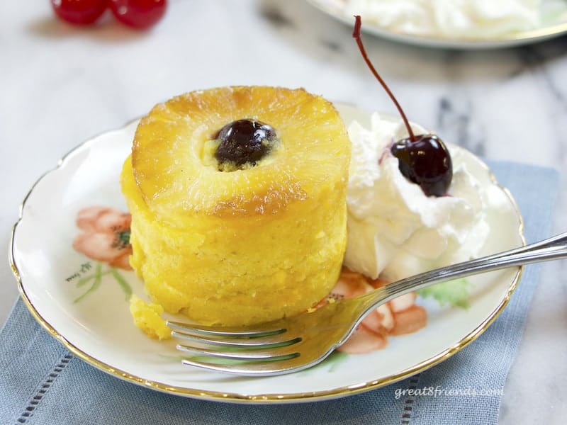 Individual serving of Pineapple Upside Down Cake with whipped cream and a cherry on the side.