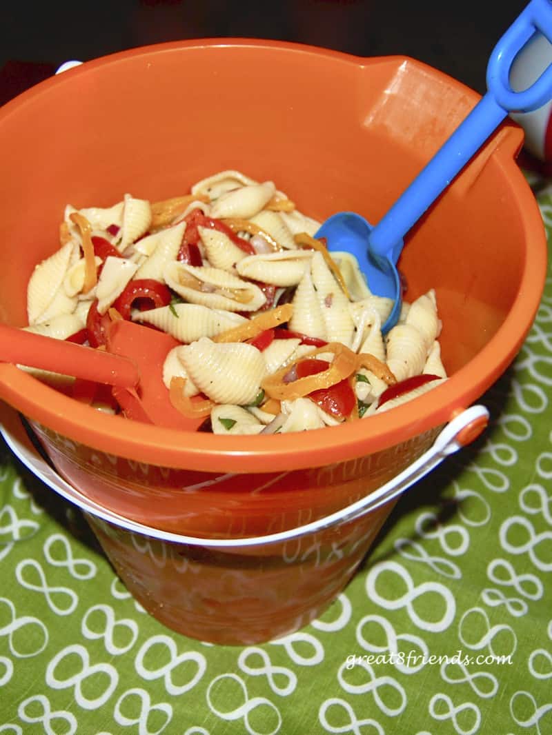 Shell Pasta in orange sand pail with plastic shovels as servers.