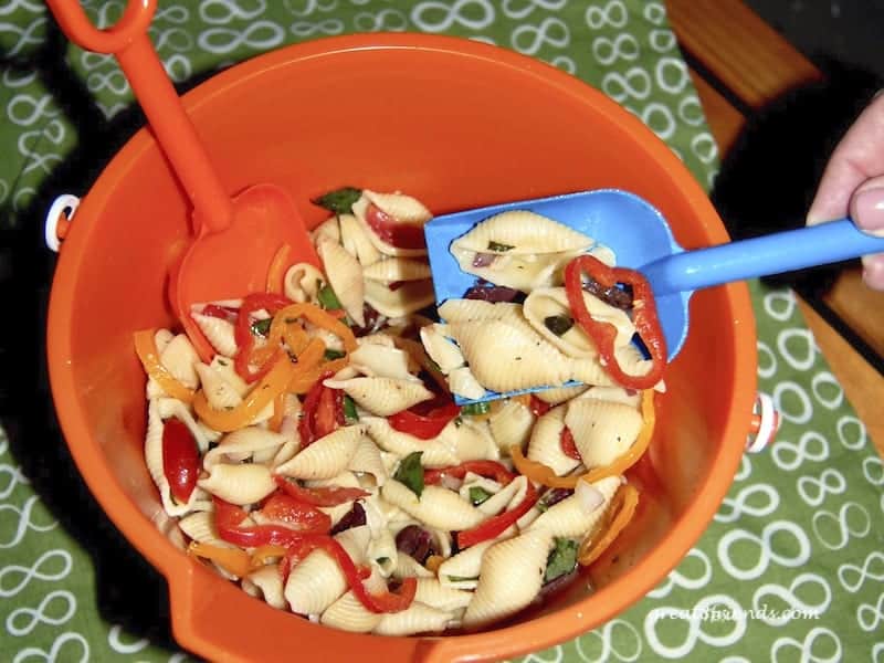 Shell pasta salad in an orange plastic beach pail.