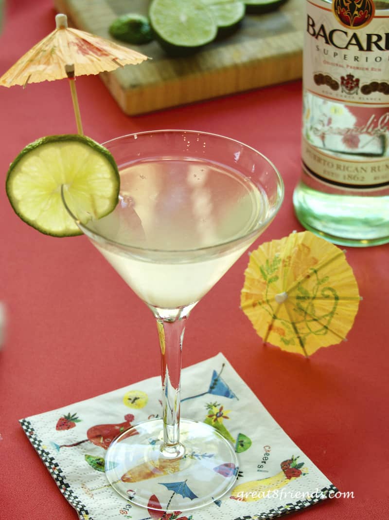 Rum Daiquiri in a martini glass garnished with a lime slice and paper umbrellas.