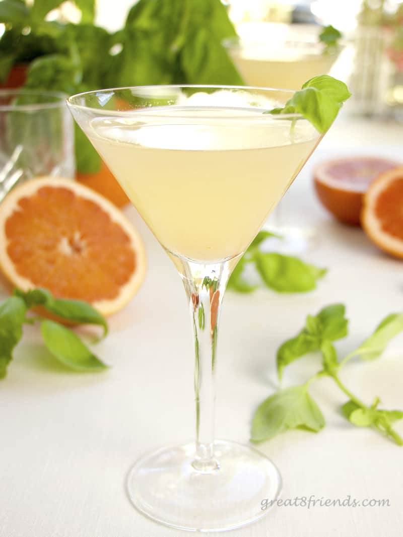 Grapefruit Basil Martini with cut oranges in the background.