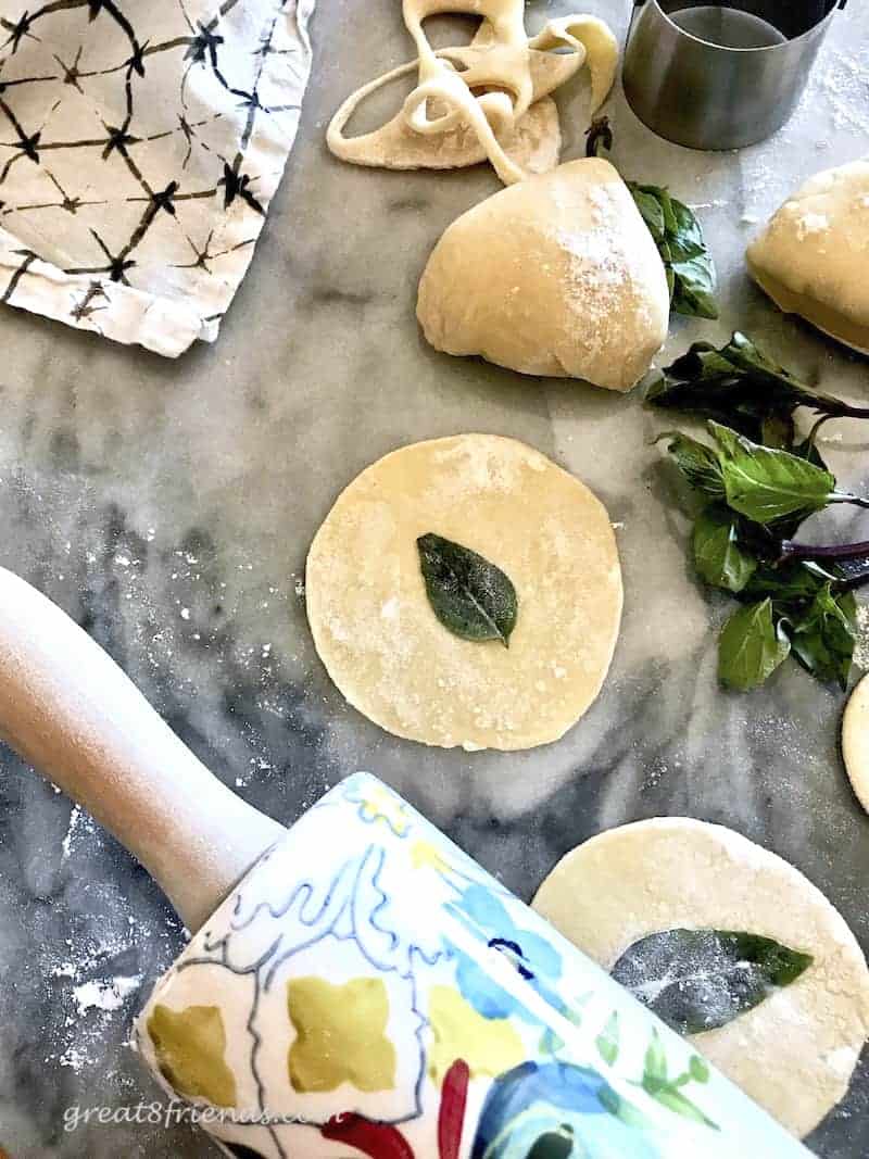 Rolling pin and ravioli circle with basil leaf.