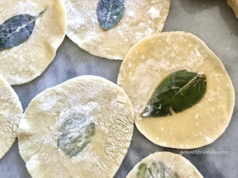 Basil leaves pressed into raw pasta circles.