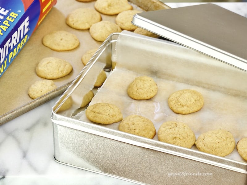Cookies being put into waxed paper lined tin.