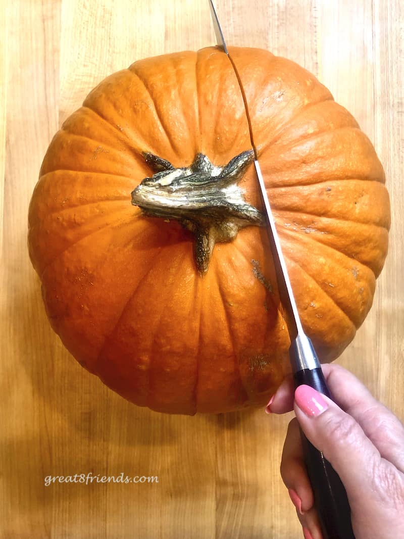 Overhead shot of pumpkin being cut with a knife.