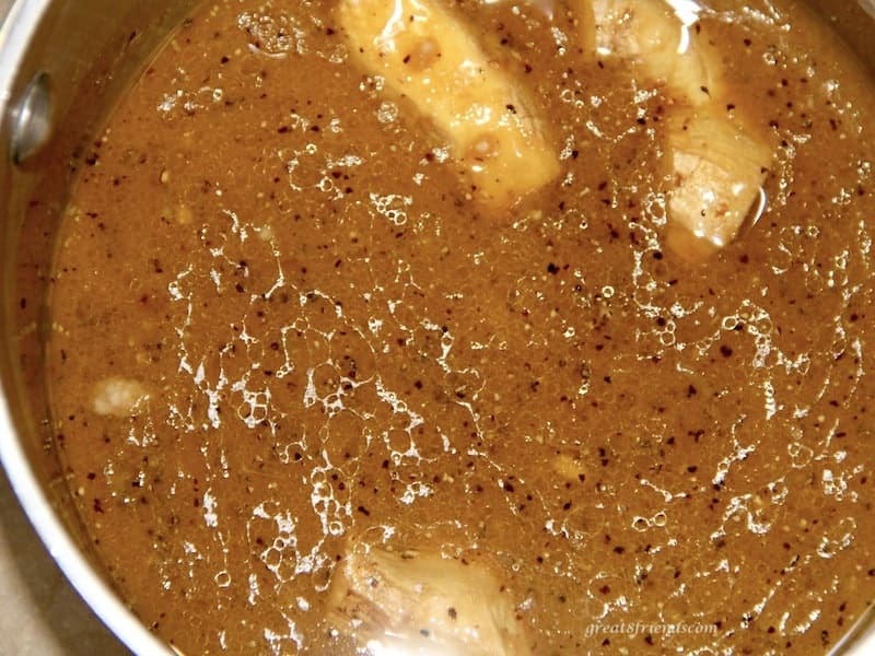 Marinade sauce simmering on the stove with fresh ginger root floating in it.