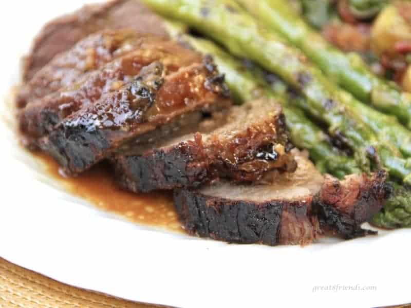 Grilled and sliced leg of lamb served with a marinade sauce and grilled asparagus.