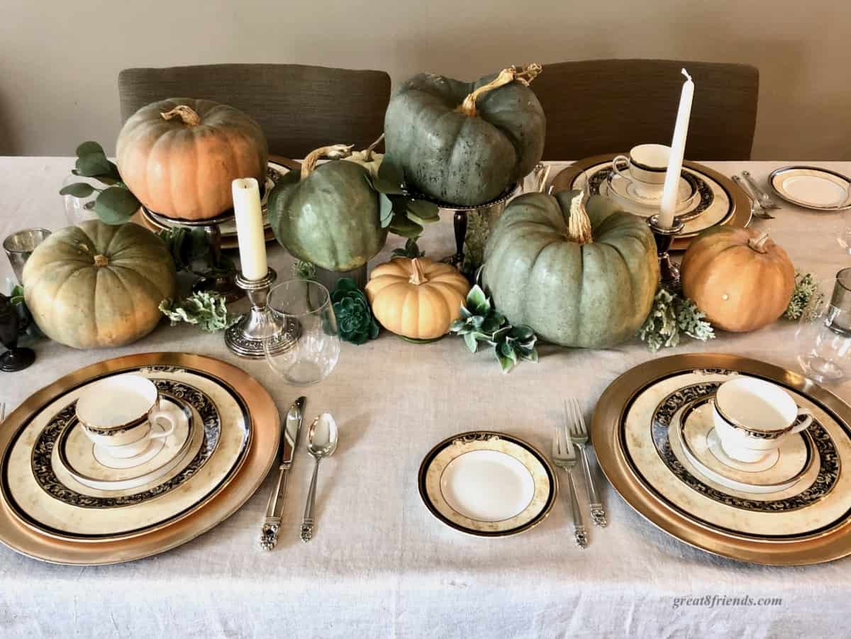 Table set with blue green and light orange pumpkins and candles for Thanksgiving.