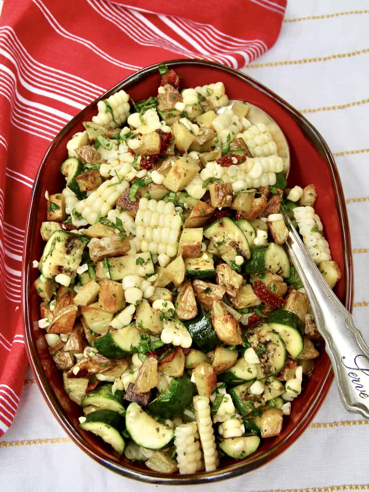 Overhead shot of potato and grilled veggie salad in a red oblong dish.