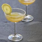 Two sidecar cocktails in couple glasses garnished with lemon slices.