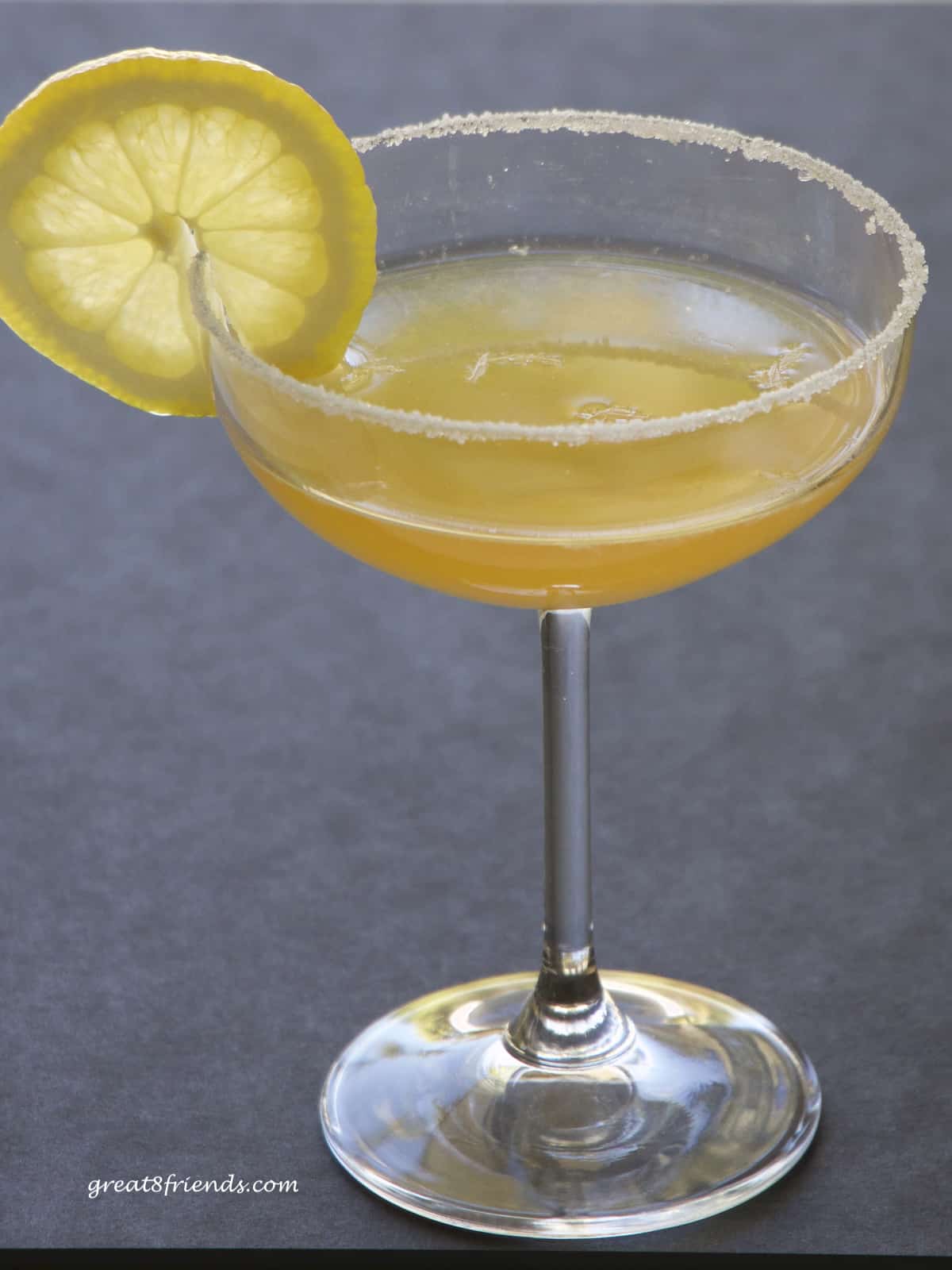 A sidecar cocktail in a coupe glass garnished with a slice of lemon.