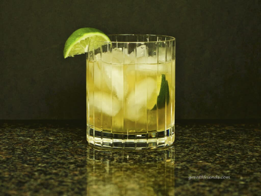 A cocktail in a double old-fashioned glass garnished with a wedge of lime. Gifts for Guys.