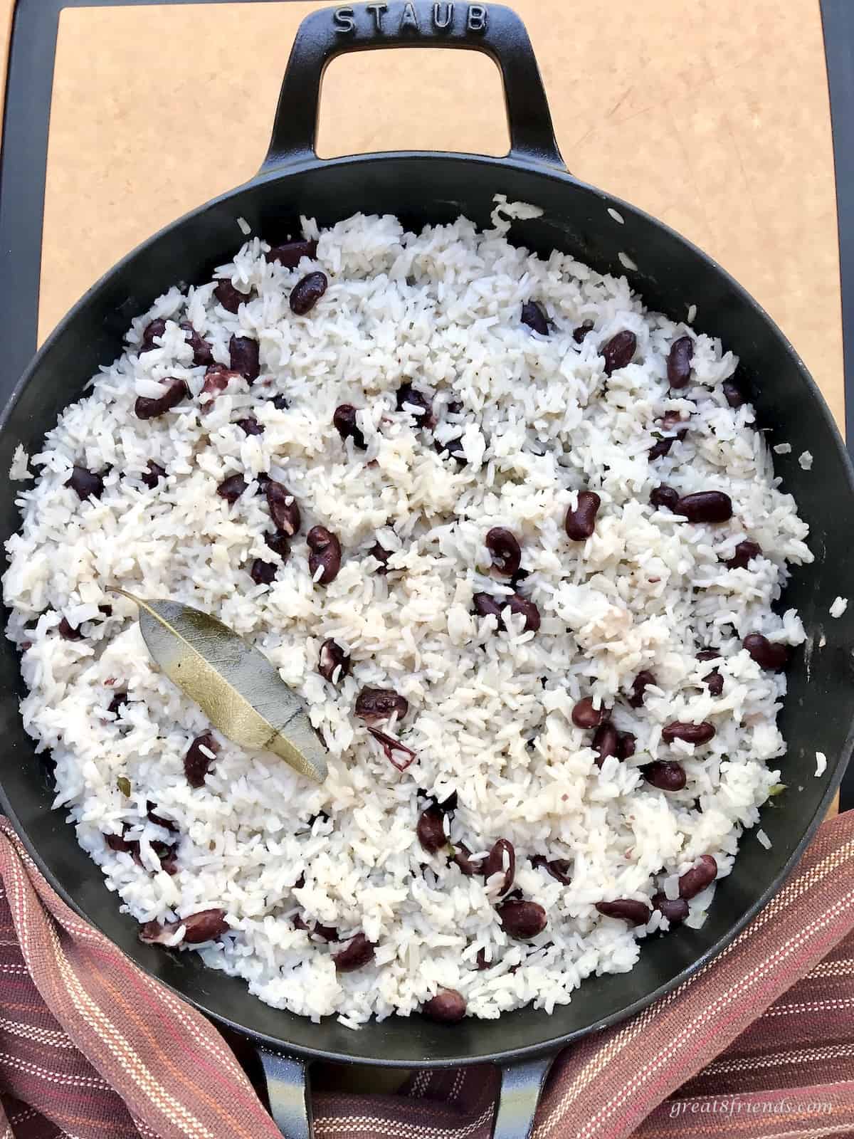 Large skillet of white rice and beans with a bay leaf on top.