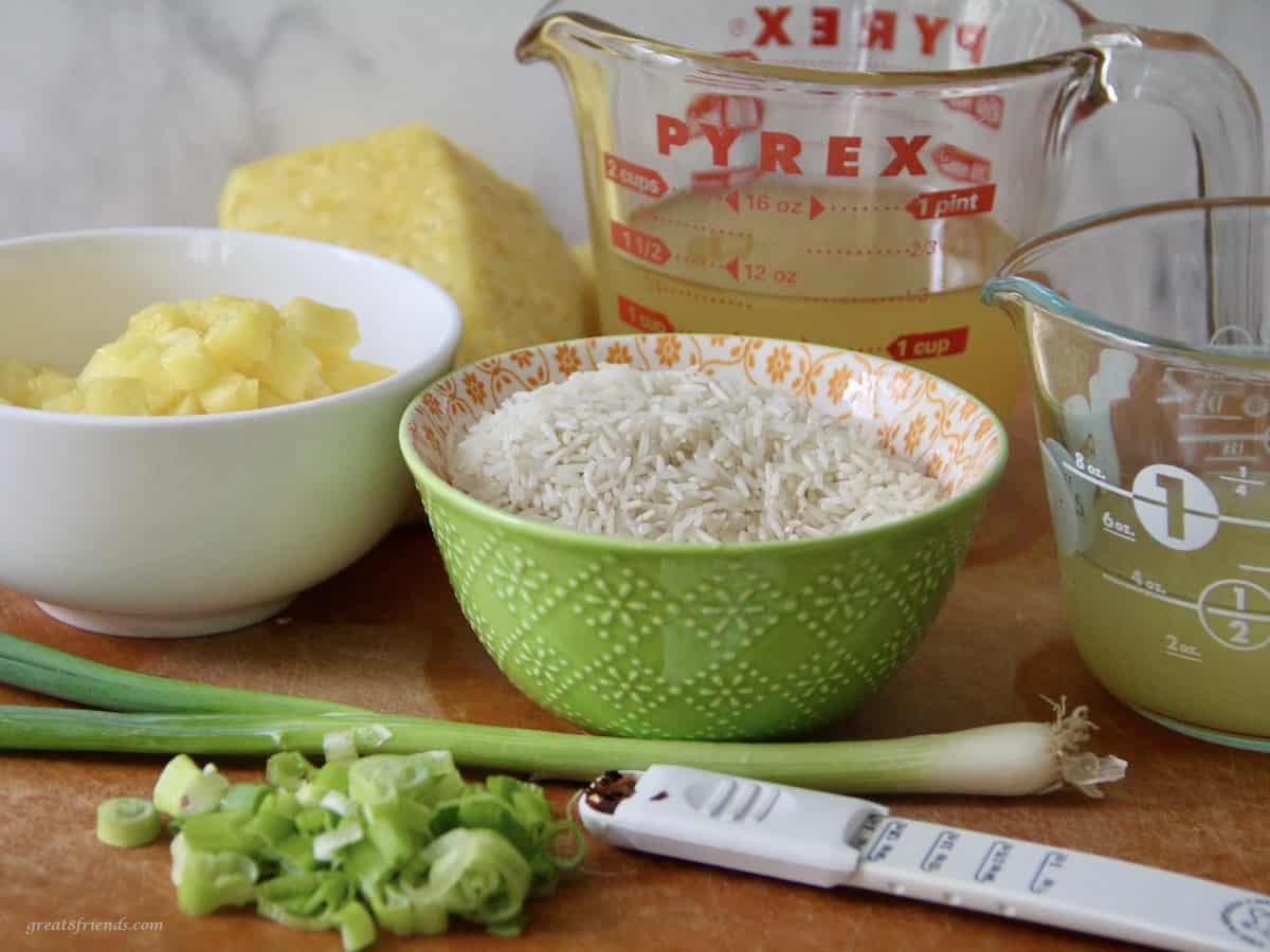 Ingredients for making pineapple rice including green onions, chicken broth, pineapple juice and red pepper flakes.