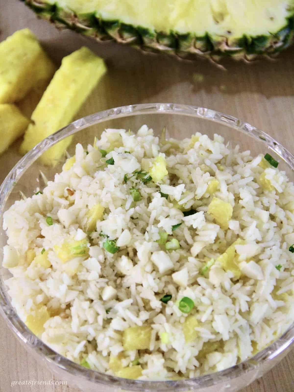 Overhead view of pineapple rice in a glass bowl with fresh pineapple in the background.