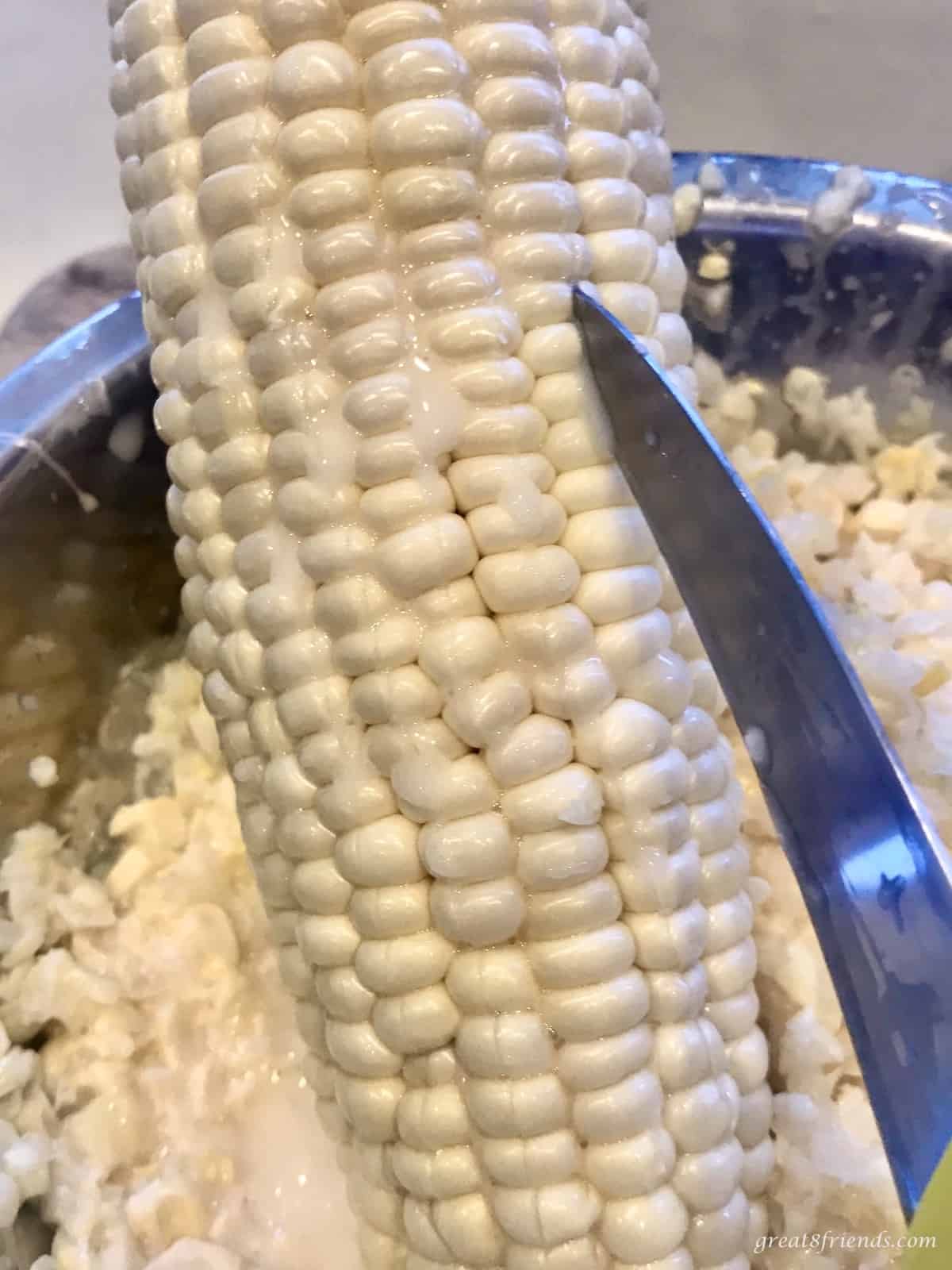 Fresh corn being "milked" with the blade of a sharp knife.