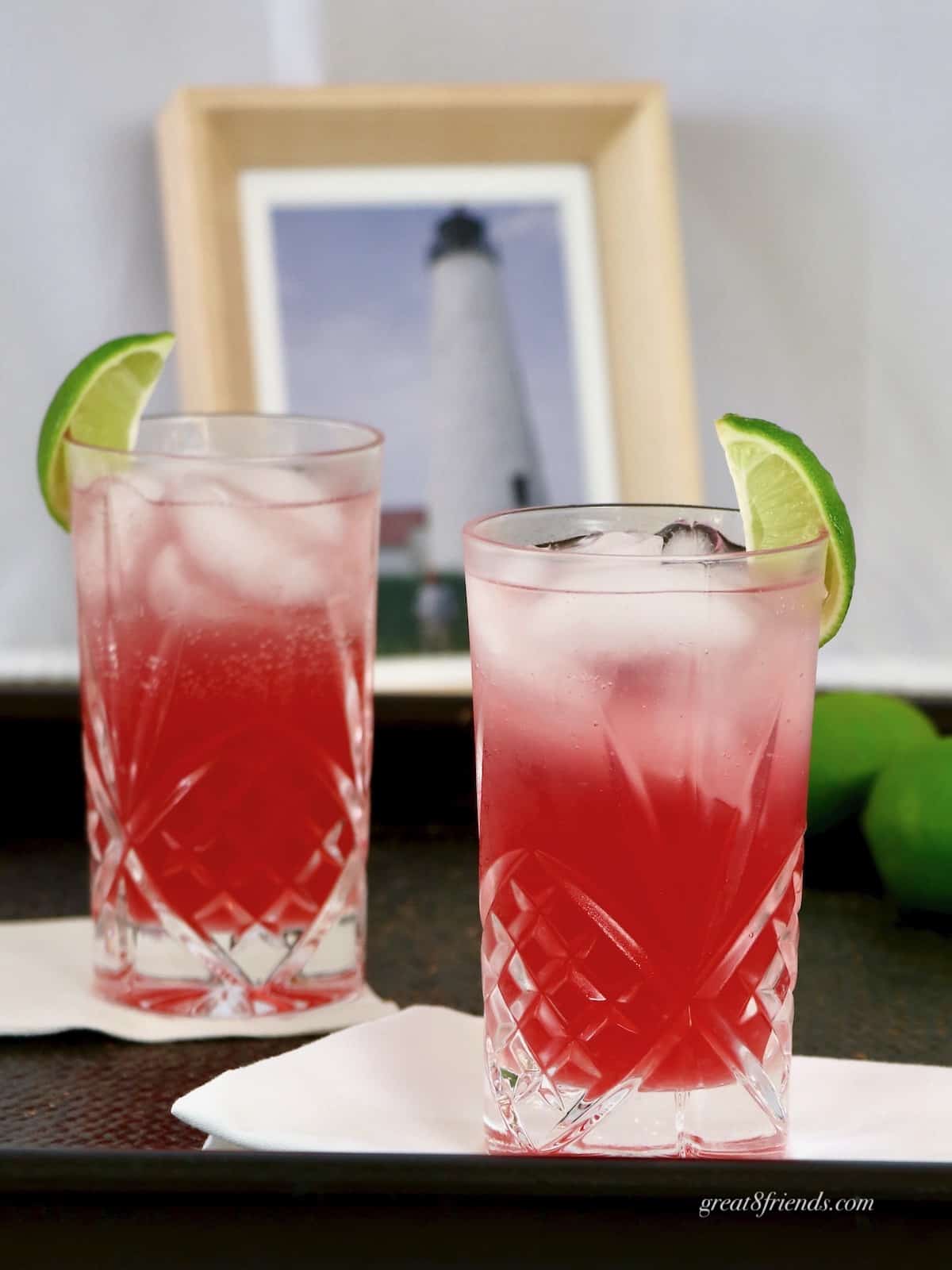 Two crystal glasses with Nantucket Seabreeze cocktail garnished with lime wedges.