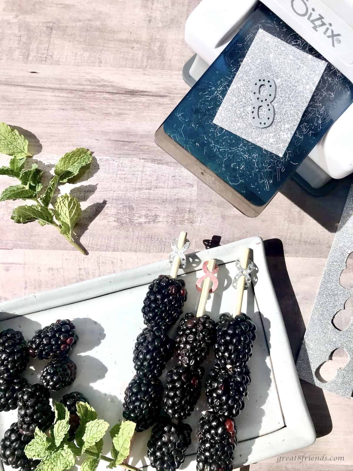 Fresh blackberries on a stick with a paper number eight on the end with a paper cutting machine on the side.