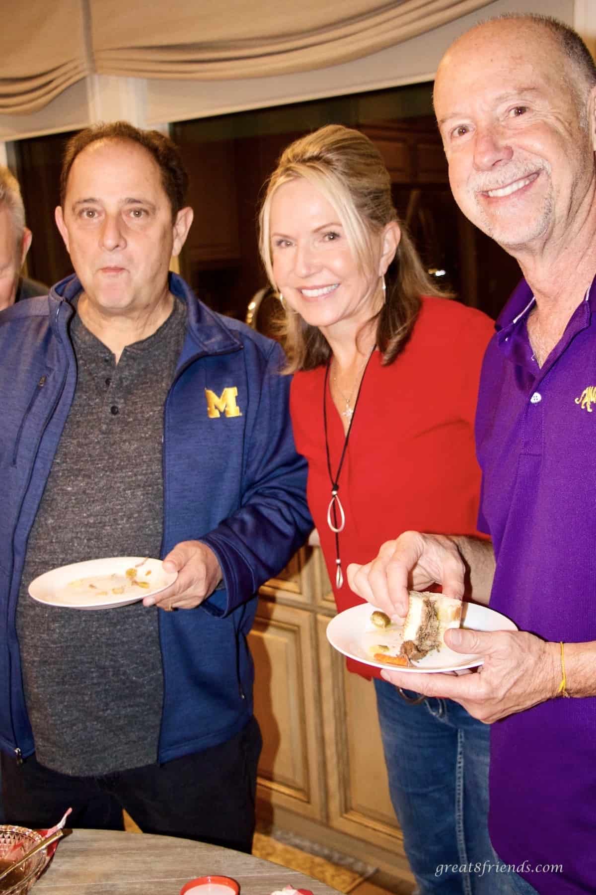 Two men and a woman posing for the camera while eating Italian beef sandwiches.