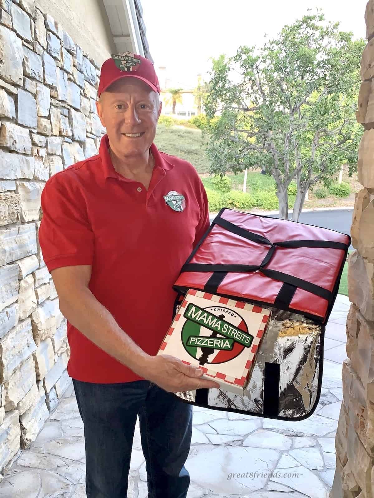 A man at a front door delivering pizza from a pizza bag.