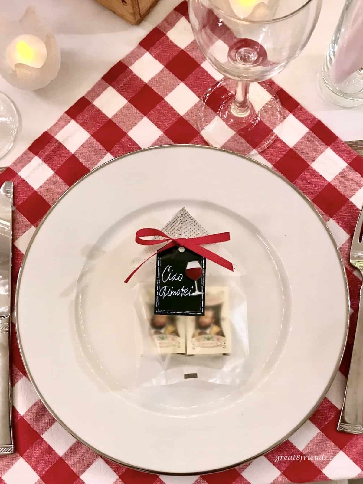 Red checked placemat with a white plate on it with a black paper place card on top.