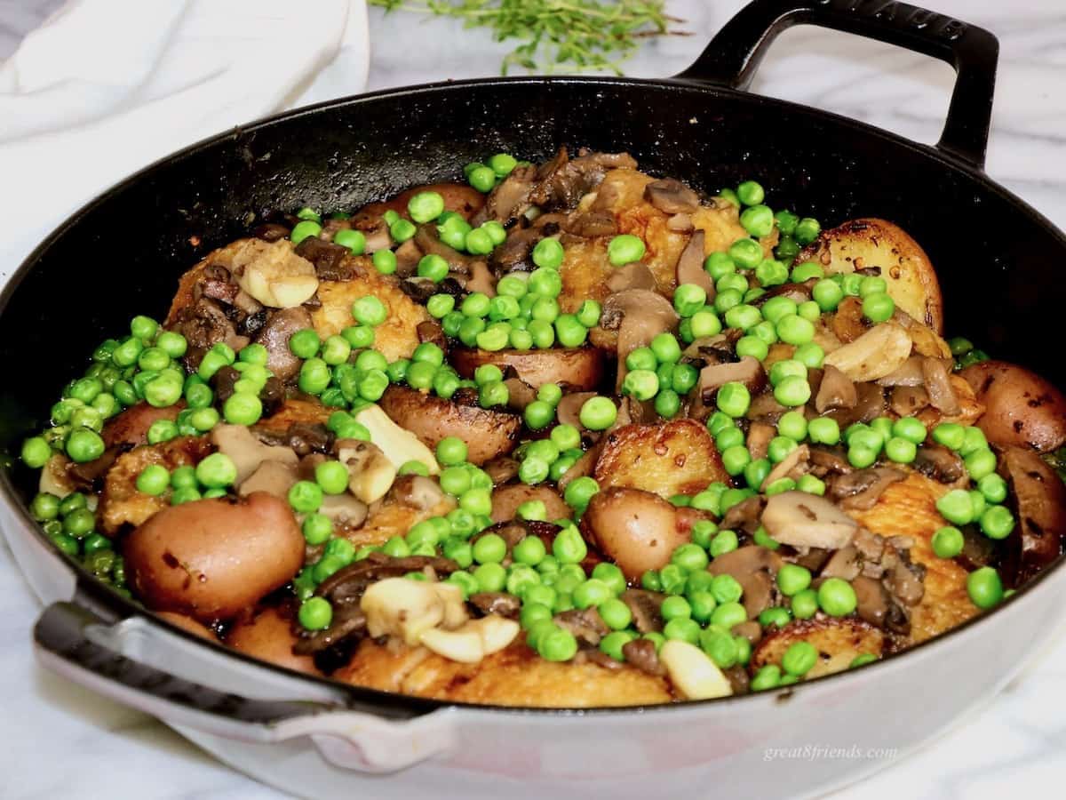 Chicken in saute pan with mushrooms, garlic and peas.