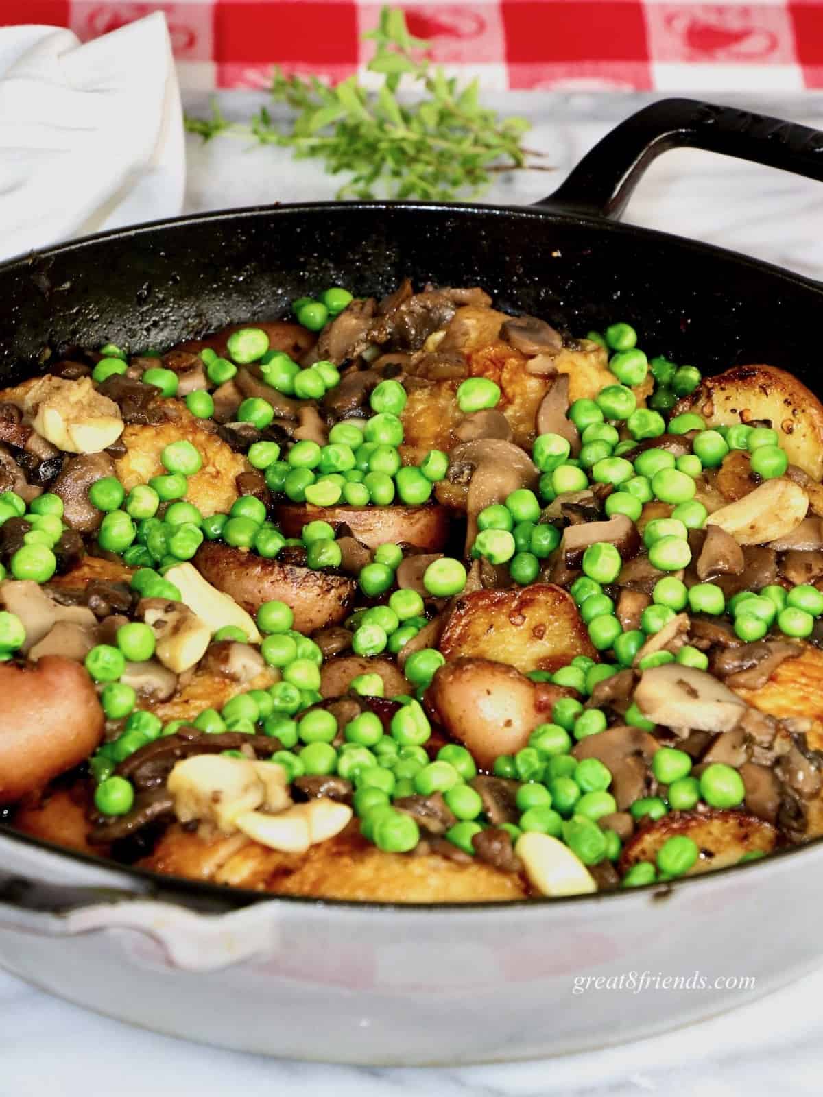 One pan meal in a saute pan with peas and mushrooms and potatoes.