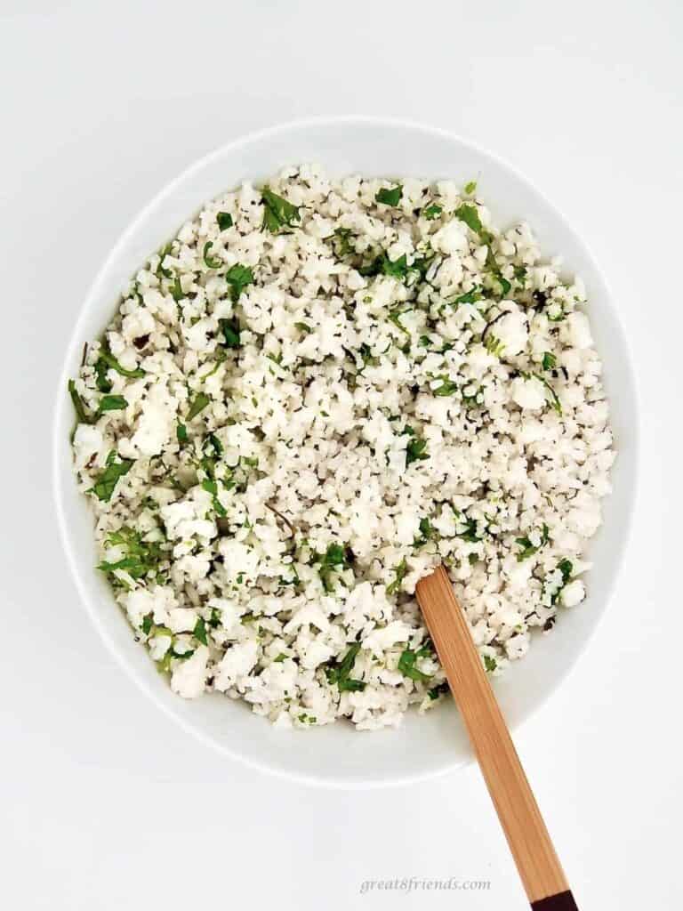 Coconut Lime Cilantro Rice in a white bowl with a wooden spoon.