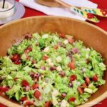 Italian Chopped Salad in a wooden bowl with salad servers in the background.