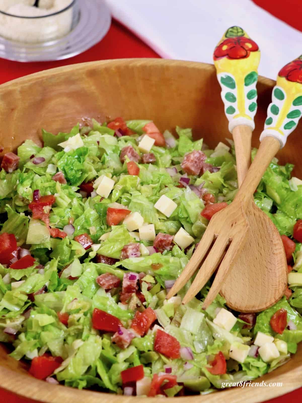 Italian Chopped Salad in a wooden bowl with salad servers.