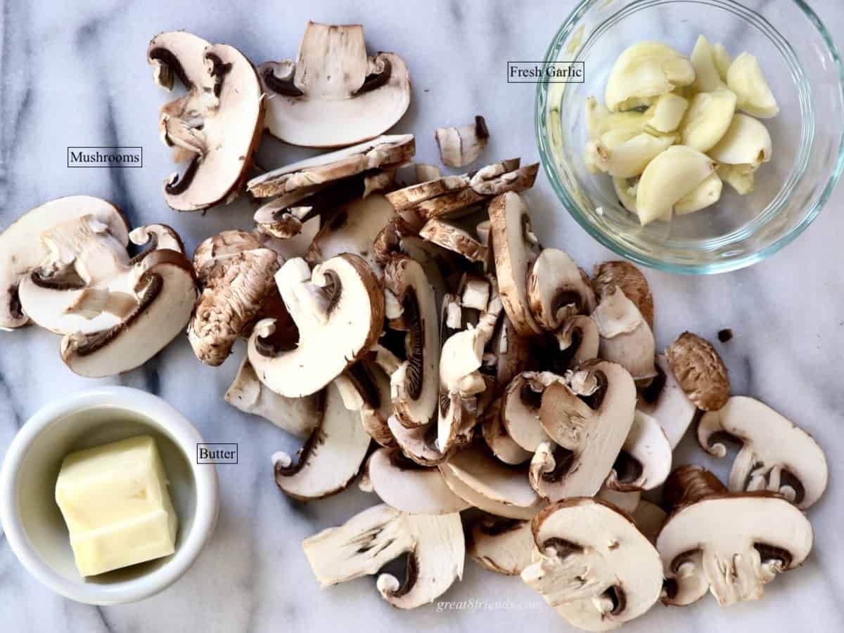 Sliced mushrooms with a bowl of fresh garlic and a bowl of butter.