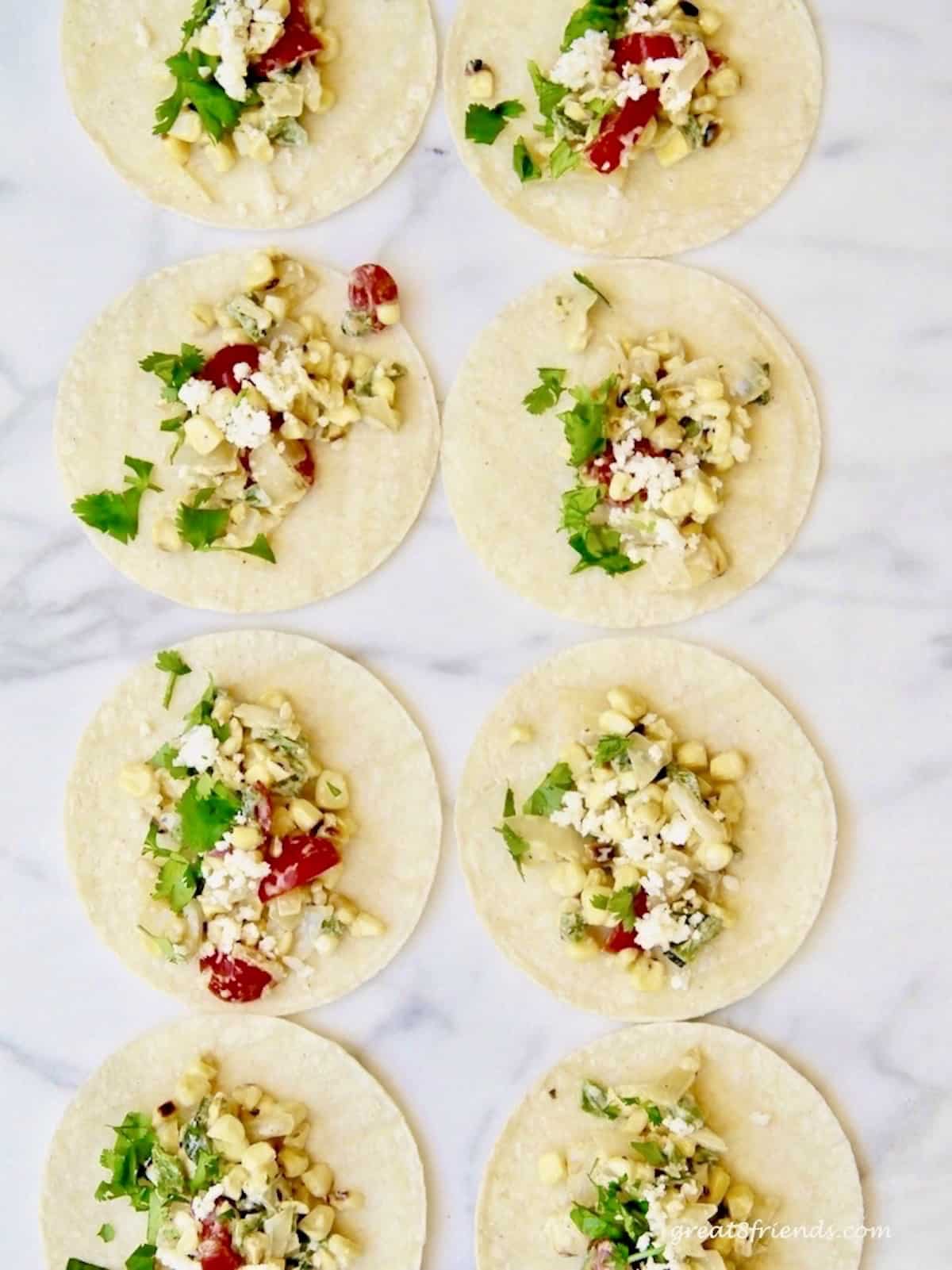 Overhead shot of 8 tortillas laying flat with fish taco filling in each.