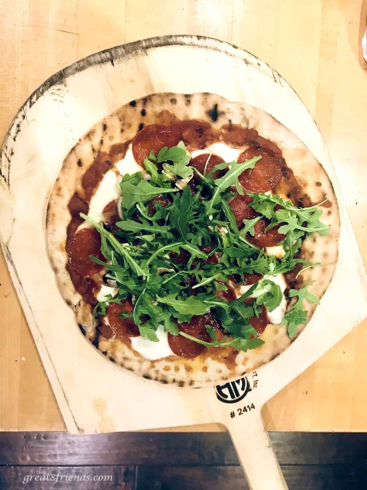 Grilled pizza with salami, cheese, pizza sauce, and arugula.