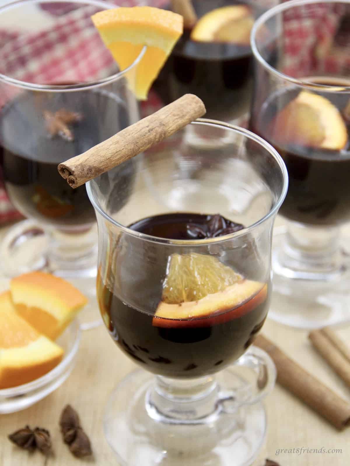 Mulled Red Wine served with a cinnamon stick and oranges.