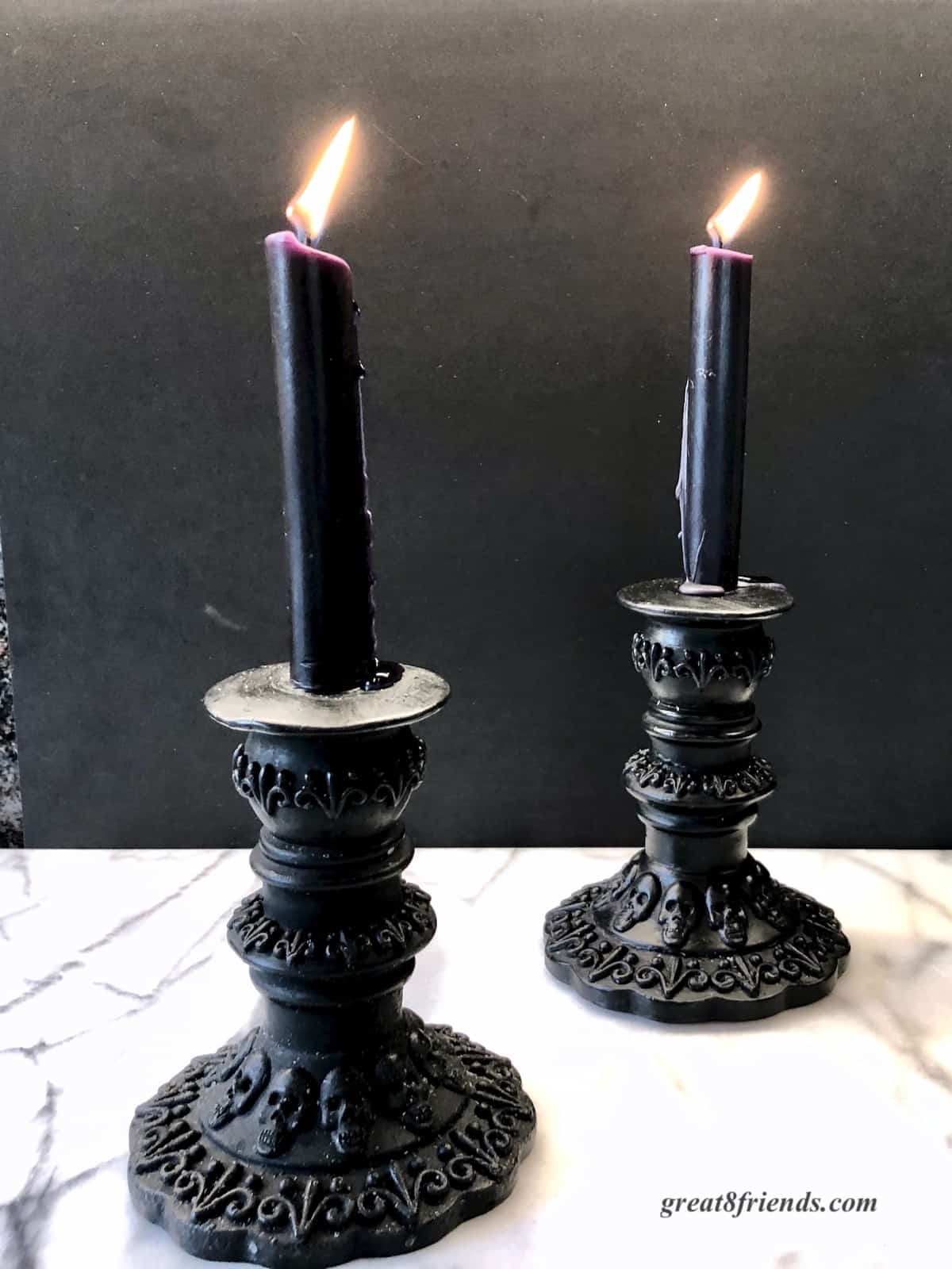 Two black halloween taper candles. The holders are embossed with skulls.