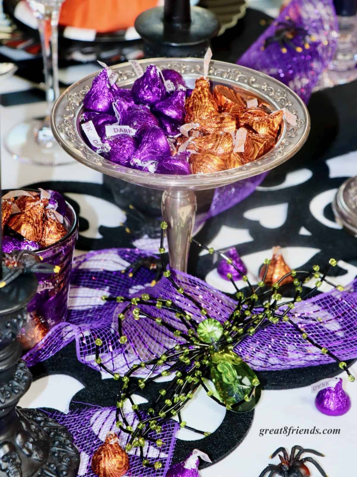 Purple and orange Hershey's kisses in dishes with a green and black plastic spider.