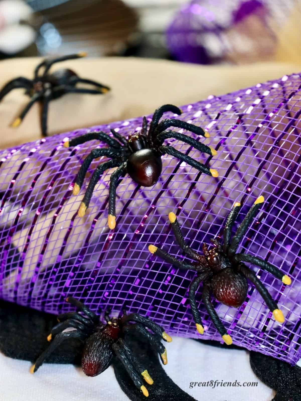 Black plastic spiders crawling on purple mesh.