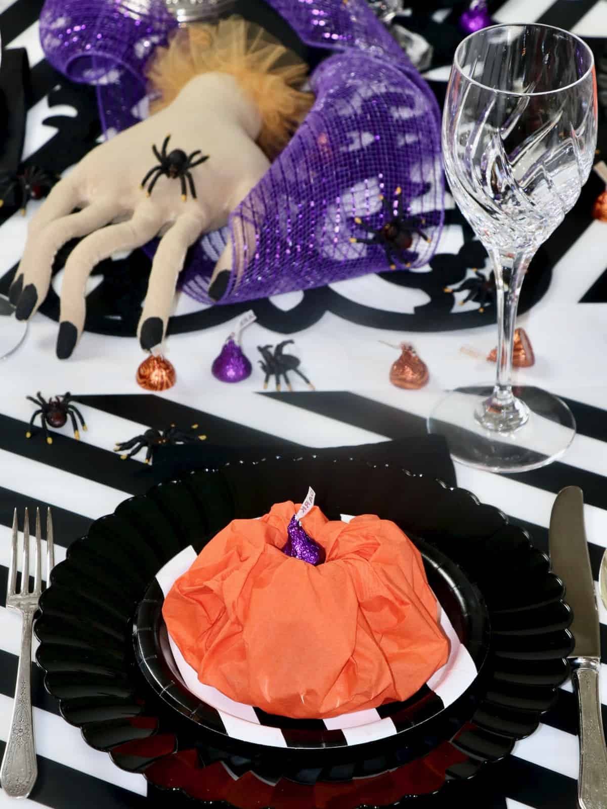 Halloween table setting with paper napkin pumpkin and creepy hand centerpiece.