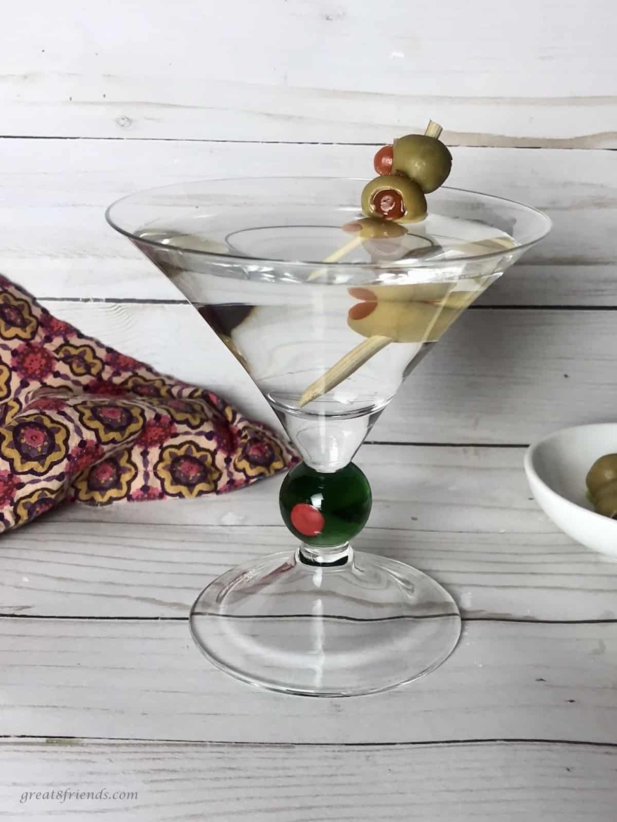 A classic gin martini with three olives on a pick.