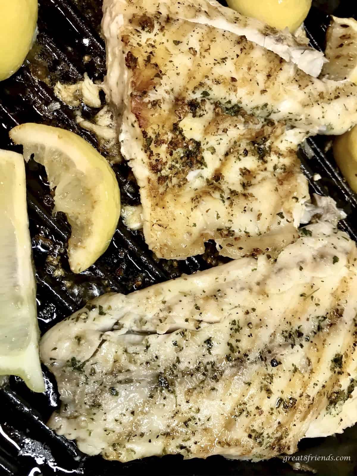 Sea Bass on the grill with lemon slices.