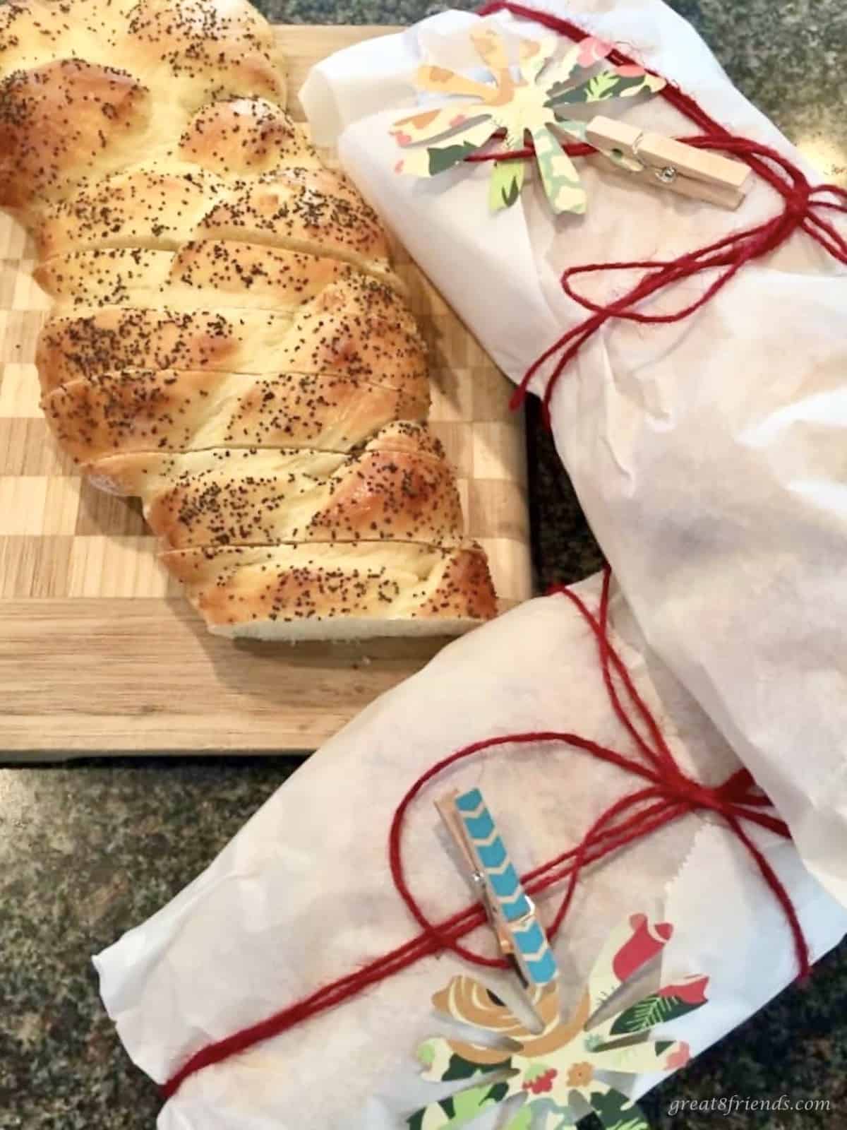 Three loaves of challah bread with two of them wrapped in white paper for a holiday gift.