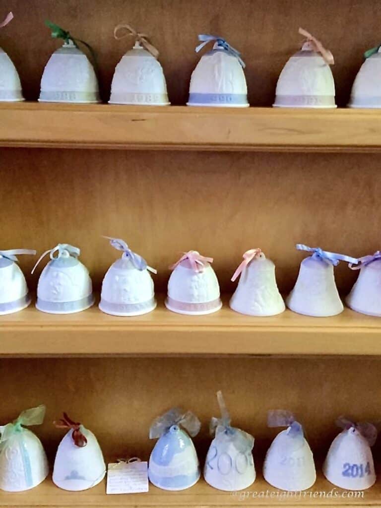 Several ceramic bells lined up on wooden shelves.