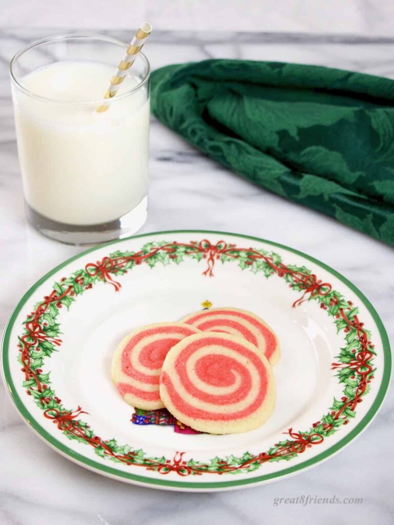 Peppermint Pinwheel Cookies on Christmas plate with a glass of milk.